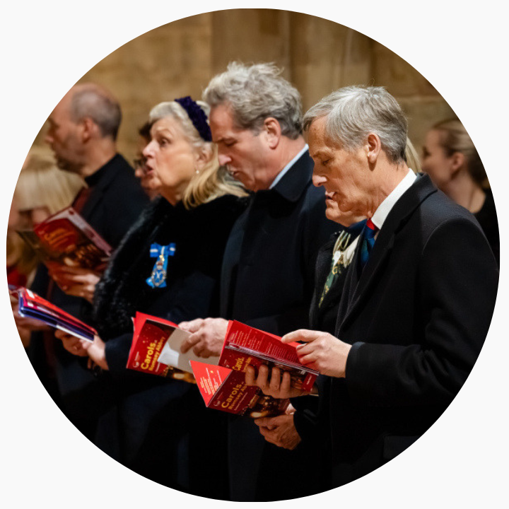 A group of people wearing coats and singing carols.