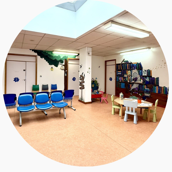 Patient waiting room with blue chairs and wooden floor.